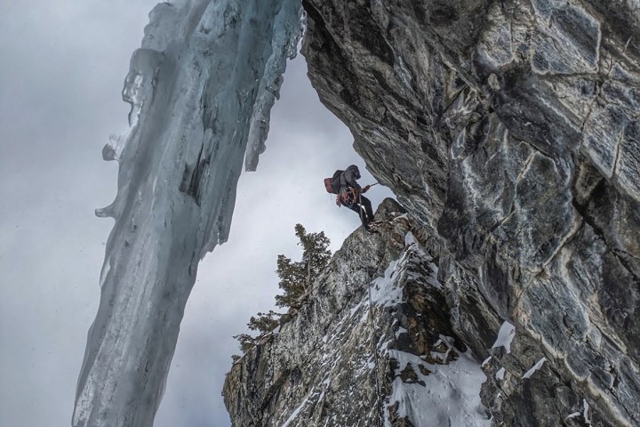 a waterfall with trees on the side of a snow covered mountain