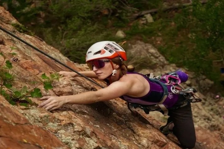 Woman in helmet rock climbing on a steep cliff.